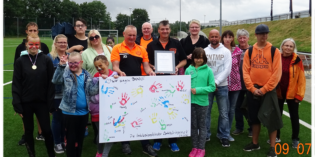 Collage aus 3 Bildern.Oben 2 Bilder nebeneinander, links eine Leinwand mit bunt gemalten Händen und Text: Wir sagen Danke. Rechts ein Blick auf das Stadion, wo ein großes Wandgraffiti zu sehen ist. Unter diesen beiden Bildern ein Gruppenbild, wo die Leinwand gezeigt wird.