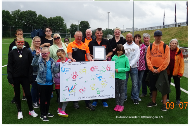 Fb5 Collage aus 3 Bildern.Oben 2 Bilder nebeneinander, links eine Leinwand mit bunt gemalten Händen und Text: Wir sagen Danke. Rechts ein Blick auf das Stadion, wo ein großes Wandgraffiti zu sehen ist. Unter diesen beiden Bildern ein Gruppenbild, wo die Leinwand gezeigt wird.